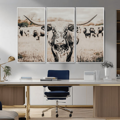 Canvas of a speckled Texas longhorn standing boldly in a field with a herd behind, perfect for rustic western or farmhouse wall decor.