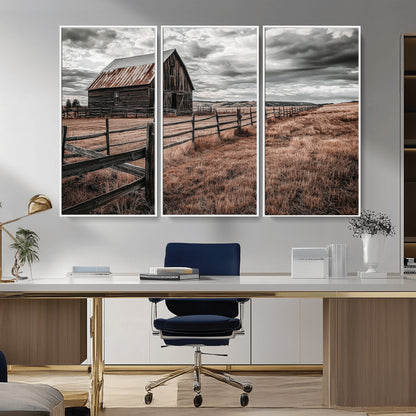 Framed canvas of a rustic barn under a moody sky with weathered fence and dark fields, ideal for farmhouse or rural-style wall decor.