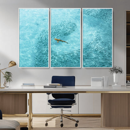 Aerial view of a shark swimming through a swirl of fish in clear turquoise waters, perfect for calm coastal or beach house decor.