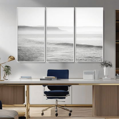 A black and white minimalist seascape featuring soft rolling waves and misty distant cliffs, creating a serene and timeless coastal atmosphere.