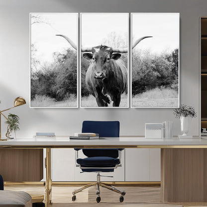 Black and white photo of a longhorn cow in a field, perfect for rustic farmhouse or western-themed interior wall decoration.