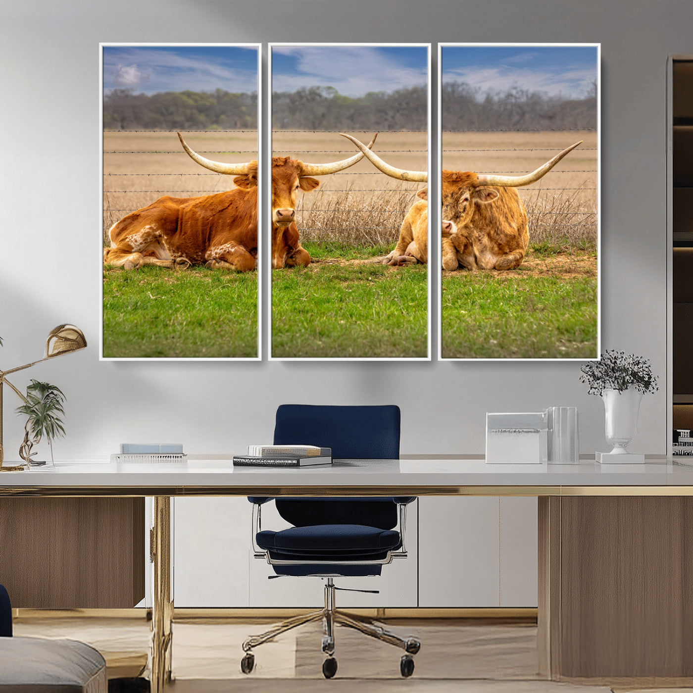 Two longhorn cows lying on green grass in front of a golden field and trees under a blue sky, perfect for rustic country wall decor.