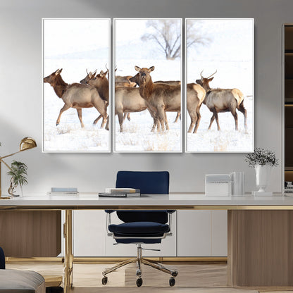 A group of elk standing on snowy terrain with a tree in the background, perfect for rustic or lodge-style winter wall decor.