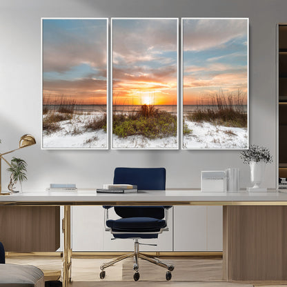 A tranquil beach scene featuring golden sunset hues over the water, with grasses in the foreground and a peaceful, serene atmosphere.