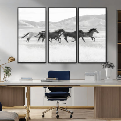A black and white image of wild horses running freely across an open grassland, capturing the power and beauty of untamed nature in a rustic western setting.