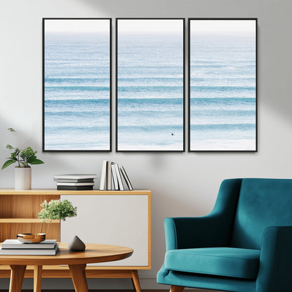 Minimalist ocean view with soft blue waves and a lone surfer, creating a serene and airy coastal aesthetic, perfect for tranquil home decor.