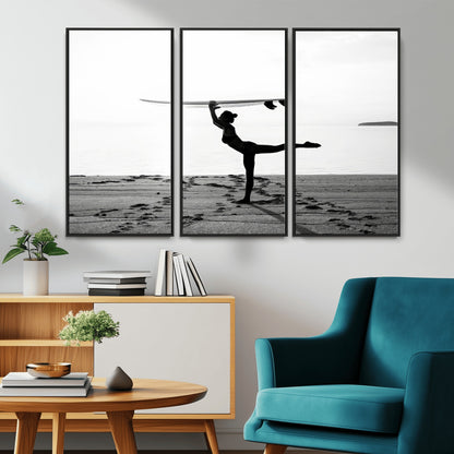 A woman balances a surfboard on her head while striking a yoga pose on the beach, silhouetted against a calm ocean horizon.