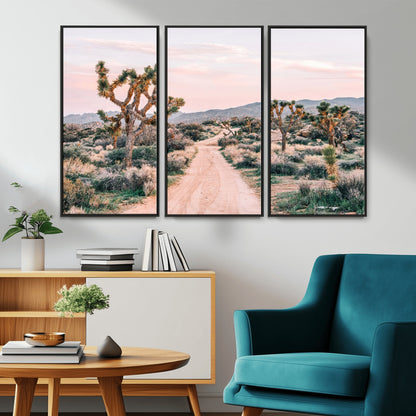 A dusty road winding through Joshua Tree National Park, framed by iconic twisted trees and warm desert tones under a soft pastel sky.