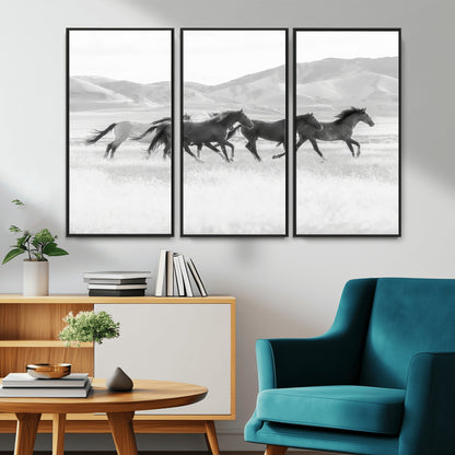 A black and white image of wild horses running freely across an open grassland, capturing the power and beauty of untamed nature in a rustic western setting.