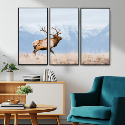 An elk walking on snowy grassland with majestic mountains in the background, ideal for rustic lodge or cabin wall decor.