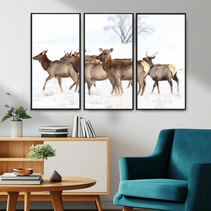 A group of elk standing on snowy terrain with a tree in the background, perfect for rustic or lodge-style winter wall decor.