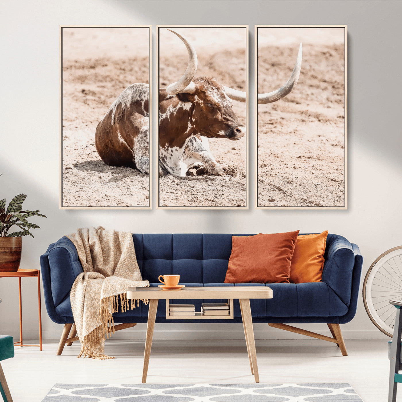 Texas Longhorn bull resting on dusty ground with warm tones, ideal for rustic western or farmhouse-themed wall decor.
