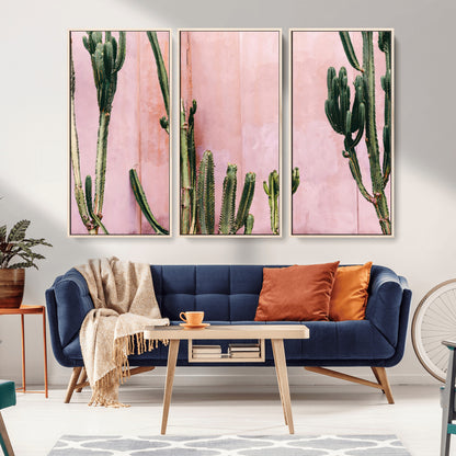Framed canvas of tall green cacti against a soft pink wall, ideal for modern desert or colorful southwest-inspired home decor.