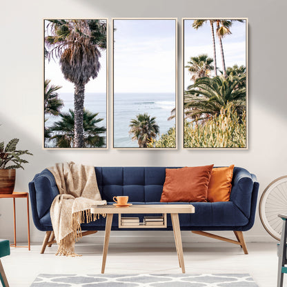 Scenic coastal view with tall palm trees overlooking a calm ocean, soft blue waves, and surfers in the distance, creating a peaceful tropical vibe.