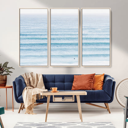 Minimalist ocean view with soft blue waves and a lone surfer, creating a serene and airy coastal aesthetic, perfect for tranquil home decor.
