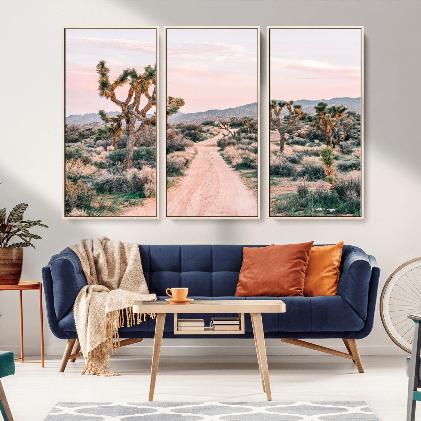 A dusty road winding through Joshua Tree National Park, framed by iconic twisted trees and warm desert tones under a soft pastel sky.