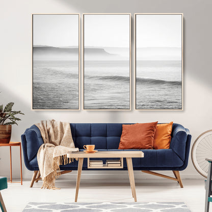 A black and white minimalist seascape featuring soft rolling waves and misty distant cliffs, creating a serene and timeless coastal atmosphere.