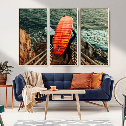 A surfer carrying a bold orange surfboard down a rugged staircase toward the ocean, bathed in golden hour light, capturing the energy of coastal adventure.