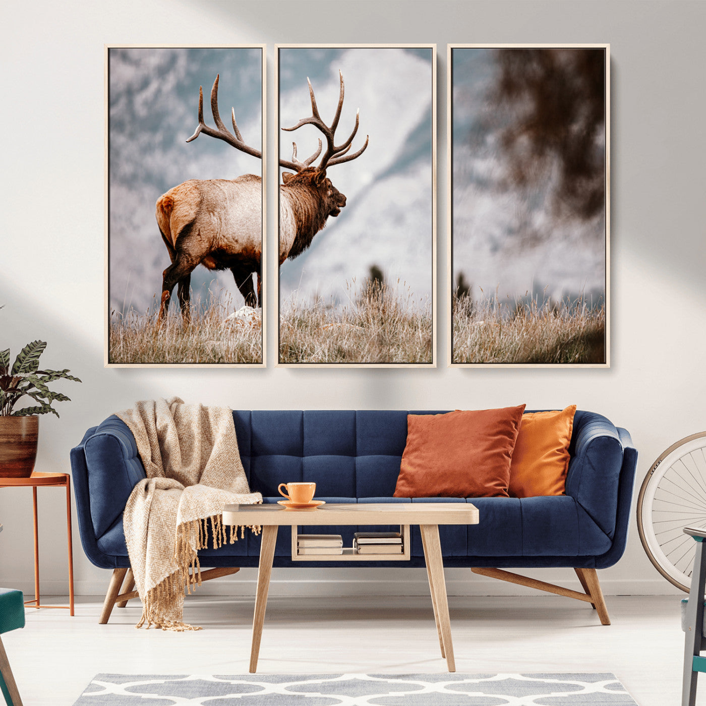 Majestic elk with large antlers standing in grass with snowy mountains in background, perfect for rustic cabin or lodge style decor.