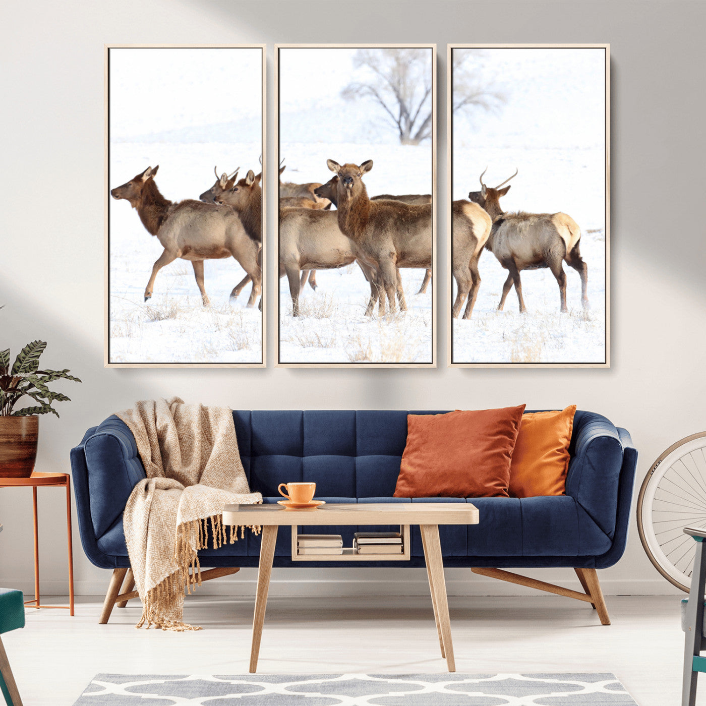 A group of elk standing on snowy terrain with a tree in the background, perfect for rustic or lodge-style winter wall decor.