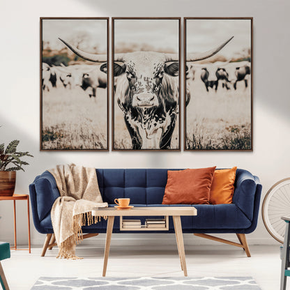 Canvas of a speckled Texas longhorn standing boldly in a field with a herd behind, perfect for rustic western or farmhouse wall decor.