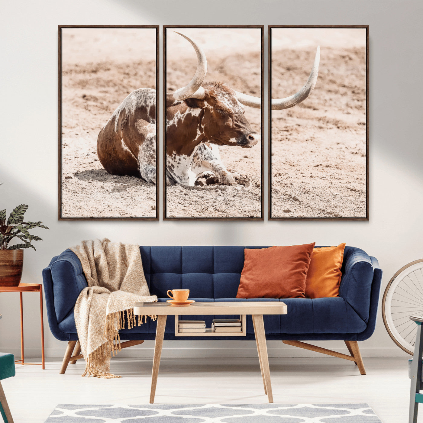 Texas Longhorn bull resting on dusty ground with warm tones, ideal for rustic western or farmhouse-themed wall decor.