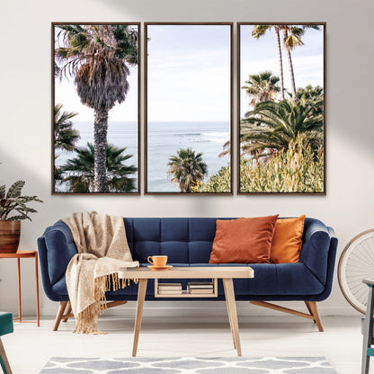 Scenic coastal view with tall palm trees overlooking a calm ocean, soft blue waves, and surfers in the distance, creating a peaceful tropical vibe.
