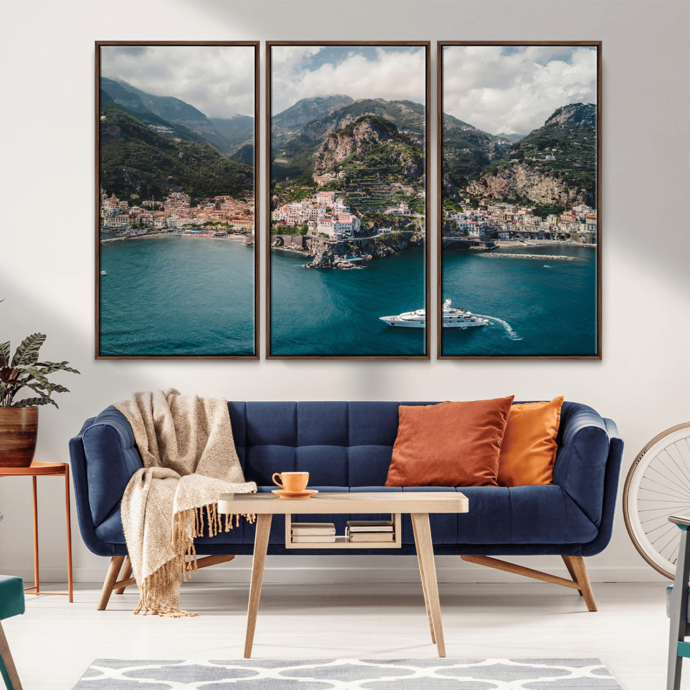 Aerial view of Amalfi Coast, Italy, with colorful hillside houses, lush green mountains, and a luxury yacht sailing in turquoise waters.