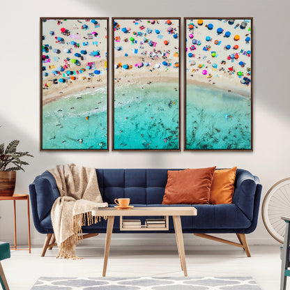 Aerial view of a vibrant beach filled with colorful umbrellas and people enjoying the turquoise ocean, capturing a lively summer vacation scene.