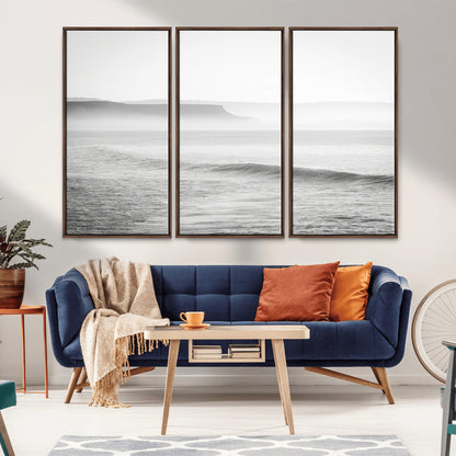 A black and white minimalist seascape featuring soft rolling waves and misty distant cliffs, creating a serene and timeless coastal atmosphere.