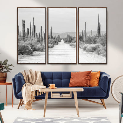 A black and white desert road stretching through a cactus-filled landscape, creating a rugged and timeless southwestern aesthetic with a sense of adventure.
