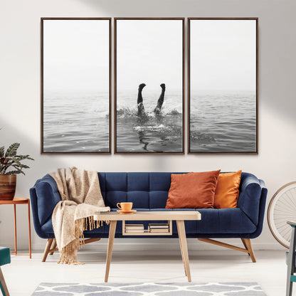 A black and white minimalist water scene capturing a playful splash as a swimmer dives upside down, creating a carefree and artistic aquatic aesthetic.