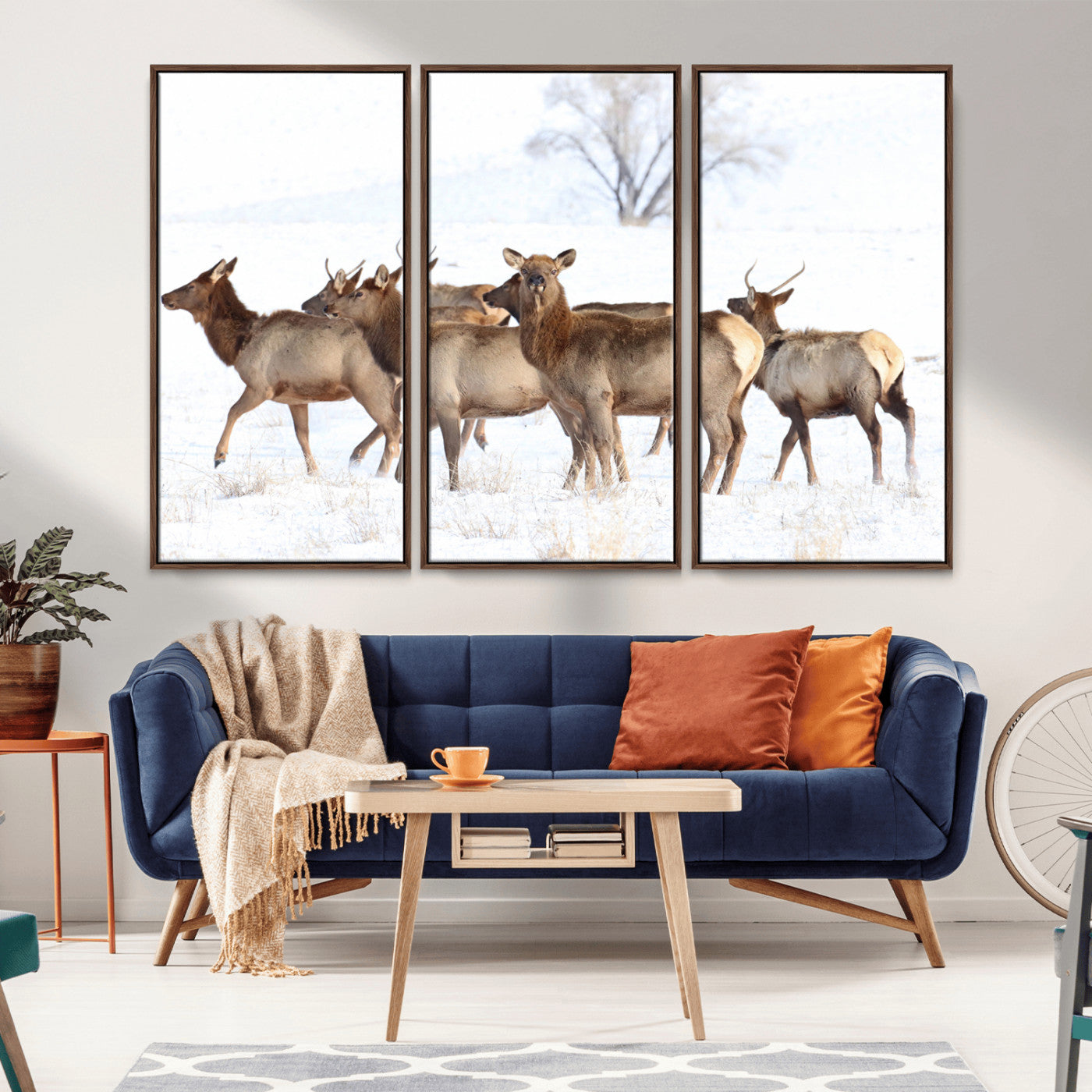 A group of elk standing on snowy terrain with a tree in the background, perfect for rustic or lodge-style winter wall decor.