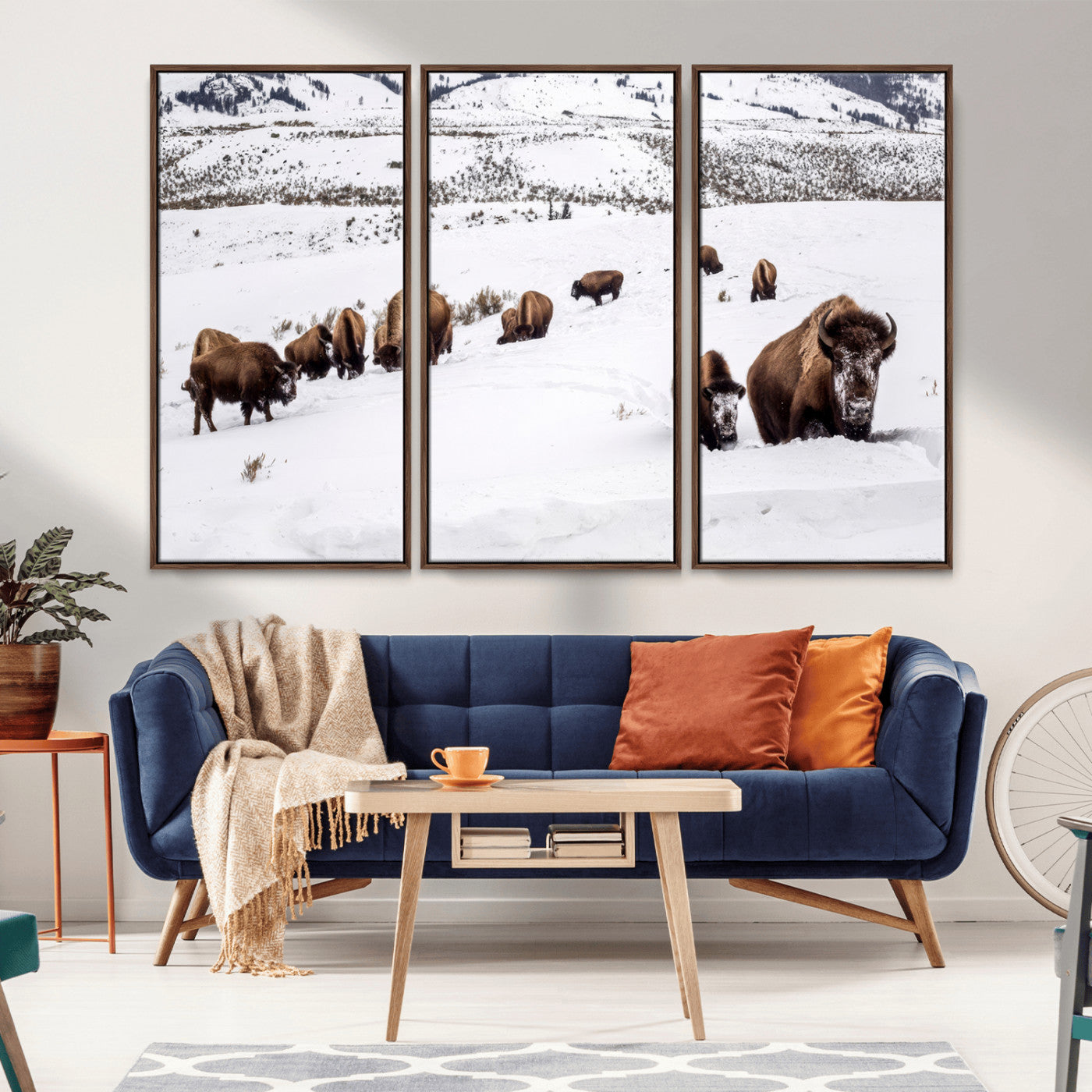 A herd of bison walking through deep snow in a mountain valley, perfect for rustic, cabin or western-themed wall decor.