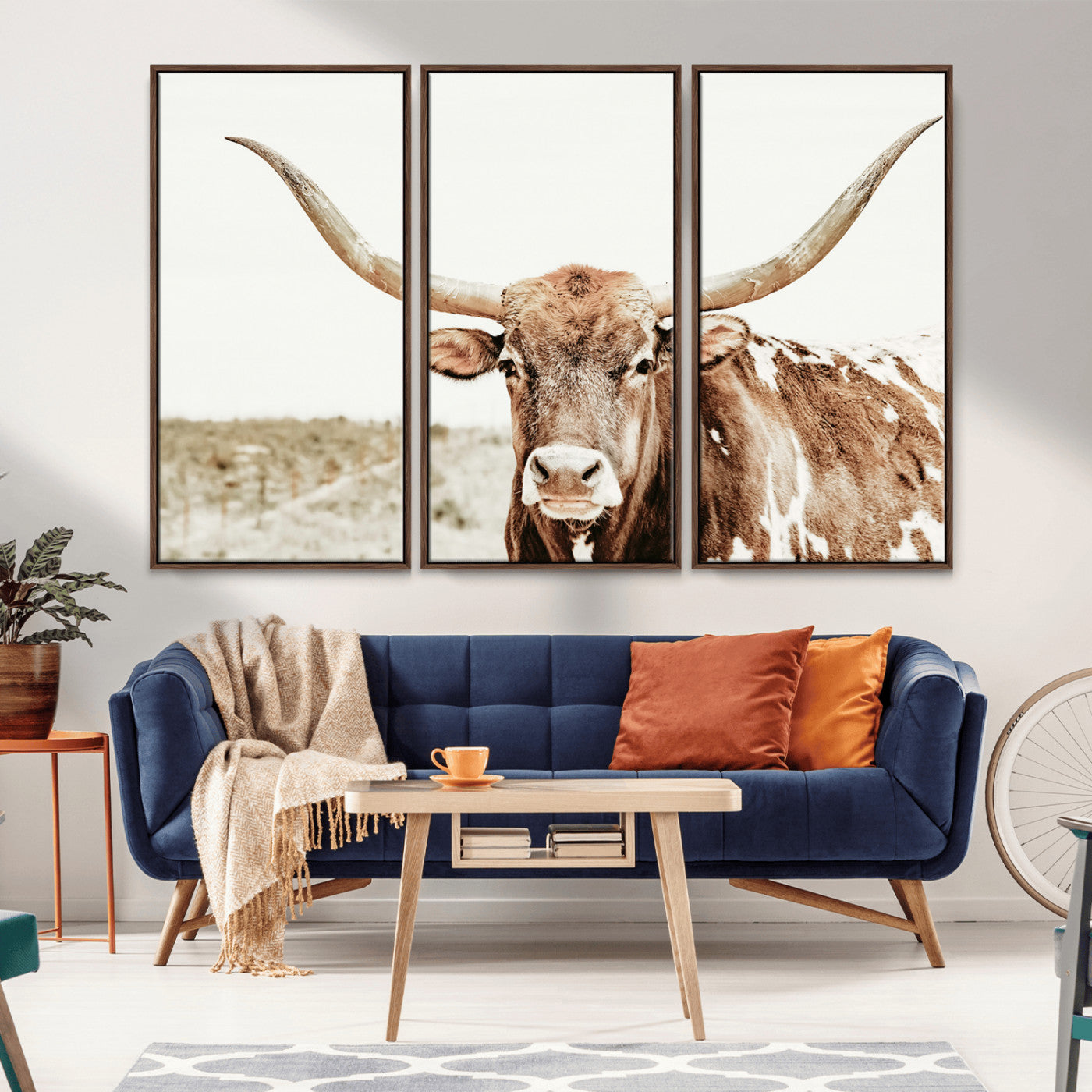 A Texas longhorn bull with wide horns, standing in a dry field under soft light, ideal for rustic farmhouse or western-themed interiors.