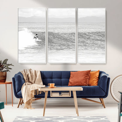 Monochrome photo of a surfer riding a wave with distant mountains, ideal for coastal motion or black and white surf-themed wall decor.