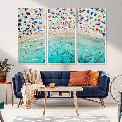 Aerial view of a vibrant beach filled with colorful umbrellas and people enjoying the turquoise ocean, capturing a lively summer vacation scene.