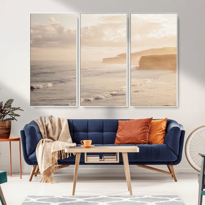 Golden hour seascape with misty cliffs and gentle waves rolling towards the shore, capturing a tranquil and warm coastal atmosphere.