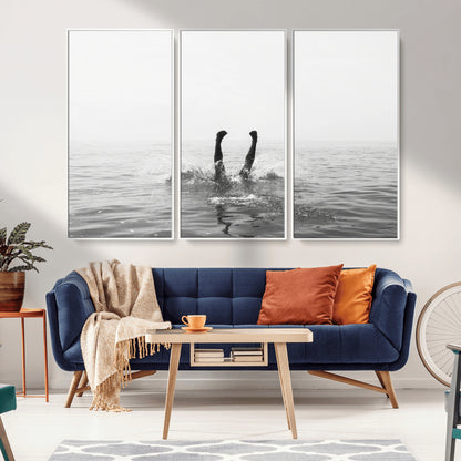 A black and white minimalist water scene capturing a playful splash as a swimmer dives upside down, creating a carefree and artistic aquatic aesthetic.