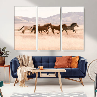 A herd of wild horses galloping through a sunlit desert plain with mountains in the background, perfect for rustic or western-themed wall decor.