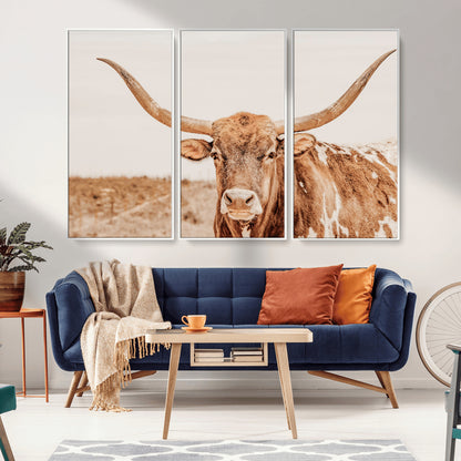 A longhorn bull standing proudly in a sunlit desert field with warm neutral tones, ideal for rustic western or farmhouse interiors.