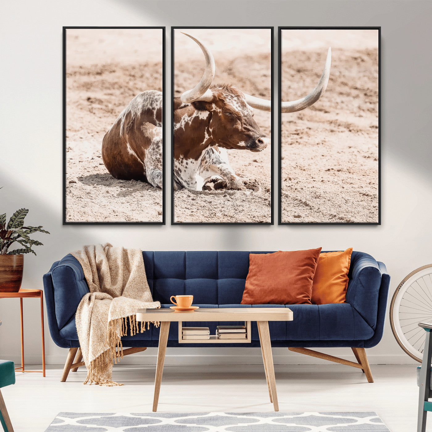 Texas Longhorn bull resting on dusty ground with warm tones, ideal for rustic western or farmhouse-themed wall decor.