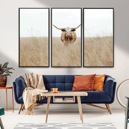 Texas Longhorn bull standing alone in dry grass with neutral tones, ideal for rustic western or cowboy-themed wall decor.