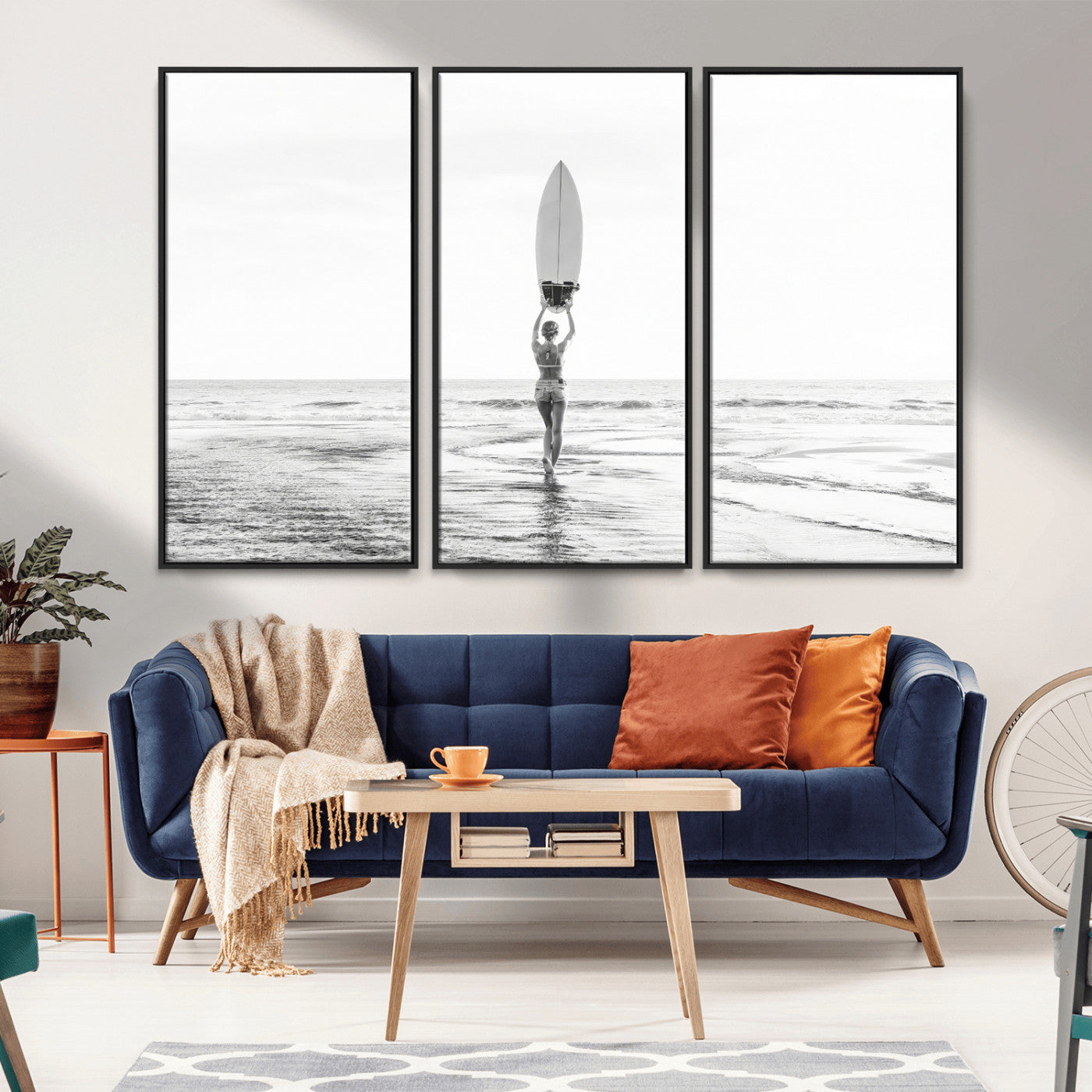 Black and white image of a female surfer holding a surfboard above her head while walking toward the ocean, creating a minimalist and bold coastal aesthetic.