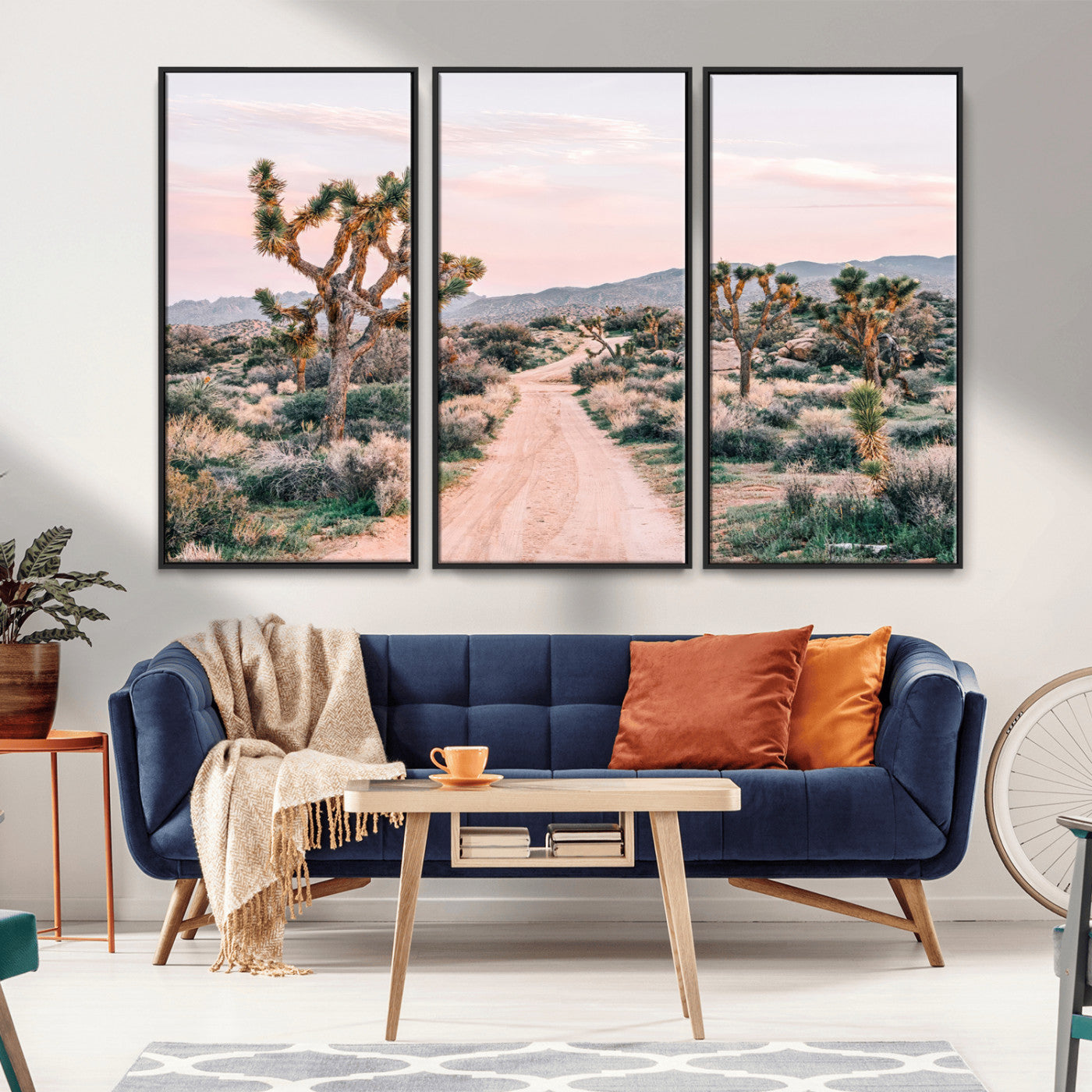 A dusty road winding through Joshua Tree National Park, framed by iconic twisted trees and warm desert tones under a soft pastel sky.
