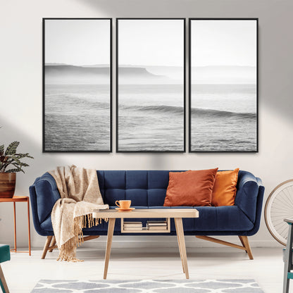 A black and white minimalist seascape featuring soft rolling waves and misty distant cliffs, creating a serene and timeless coastal atmosphere.