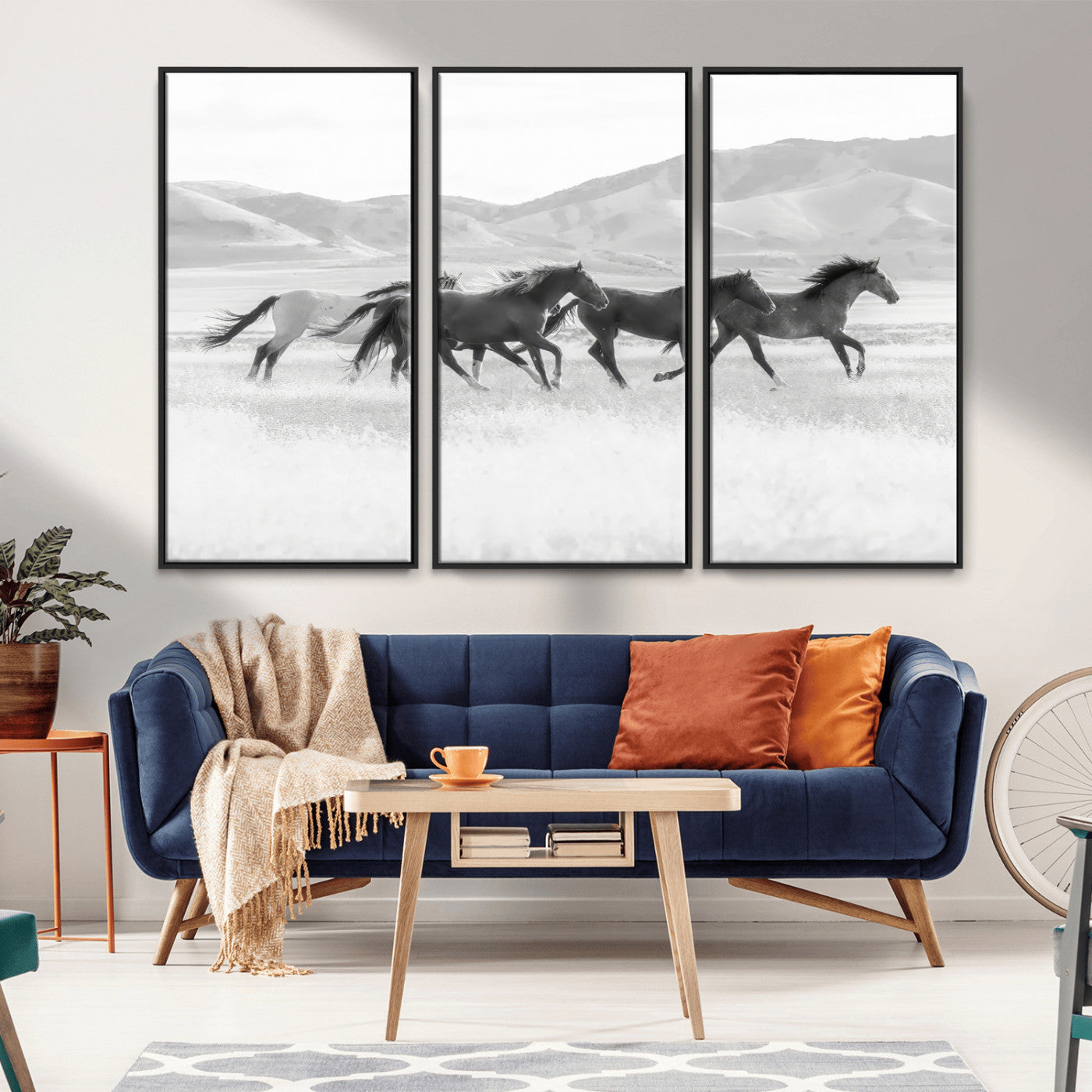 A black and white image of wild horses running freely across an open grassland, capturing the power and beauty of untamed nature in a rustic western setting.