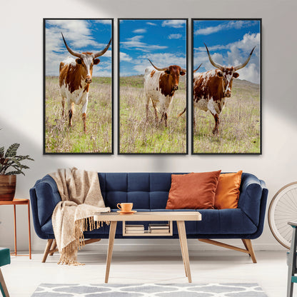 Three Texas longhorn cattle standing in dry grass under a bright blue sky, ideal for farmhouse or western rustic home decor.