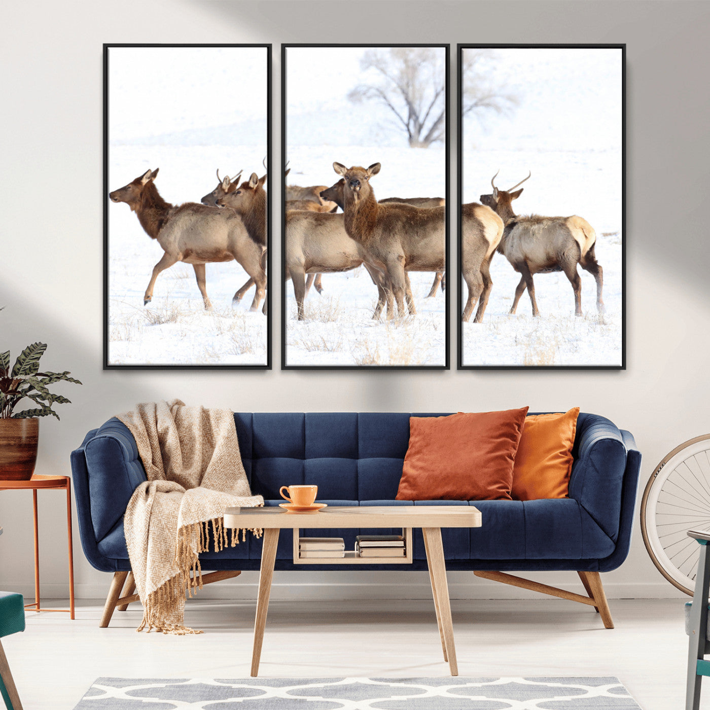 A group of elk standing on snowy terrain with a tree in the background, perfect for rustic or lodge-style winter wall decor.