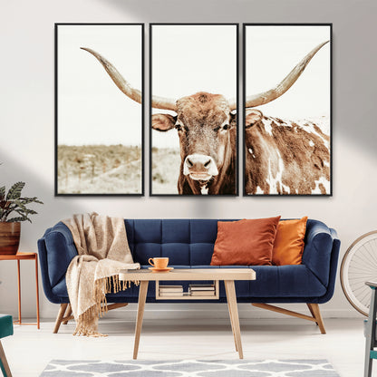A Texas longhorn bull with wide horns, standing in a dry field under soft light, ideal for rustic farmhouse or western-themed interiors.